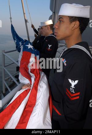 US Navy Sailors and Marines assigned to the color guard aboard the amphibious assault ship USS Iwo Jima (LHD 7) prepare to raise the American Flag during morning colors Stock Photo