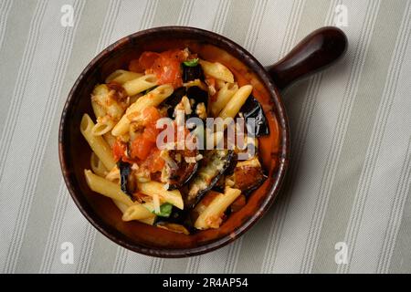 Pasta alla Norma or Penne Rigate with Eggplant and Tomato Sauce and Ricotta in a Rustic Terracotta Bowl Stock Photo