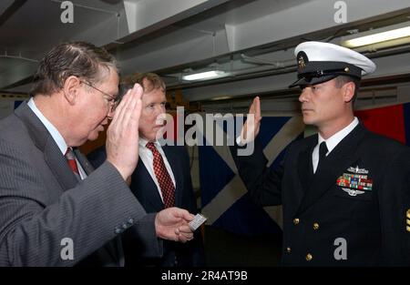 US Navy  Rep. Randy Duke Cunningham (R-CA), left, and Bill Irish Driscoll, center, take part in the reenlistment ceremony aboard USS Ronald Reagan (CVN 76). Stock Photo