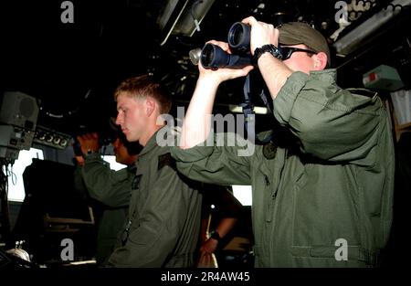 US Navy  Lt.j.g. right, and Gunners Mate 3rd Class stand watch on the bridge of the Cyclone-class patrol coastal boat USS Chinook (PC 9). Stock Photo