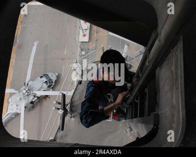 US Navy  Electronics Technician 3rd Class performs maintenance on a safety rail. Stock Photo