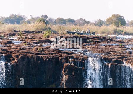 Victoria Falls, Zimbabwe, August 7, 2022. A tour boat is passing along the upper part of Vic Falls. Stock Photo