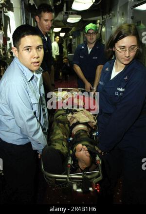 US Navy  Stretcher-bearers transport a Sailor with simulated injuries to medical during a mass casualty drill aboard the conventionally powered aircraft carrier USS Kitty Hawk (CV 63). Stock Photo