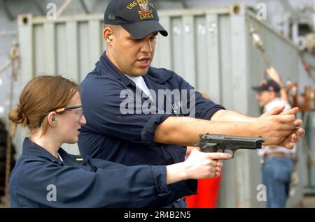 US Navy  Gunner's Mate Seaman instructs Ens. on how to fire a 9mm handgun. Stock Photo