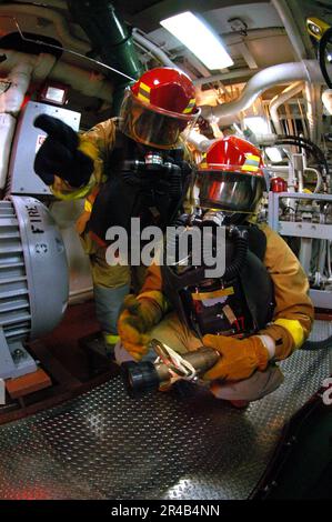 US Navy  The hose team leader from Repair Locker 3, tells his number one nozzleman the proper technique to set a re-flash watch. Stock Photo