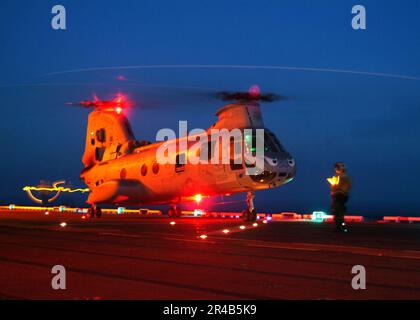 US Navy  A Landing Signal Enlisted (LSE) Sailor prepares a CH-46 Sea Knight helicopter for lift-off on the flight deck aboard the amphibious assault ship USS Tarawa (LHA 1). Stock Photo