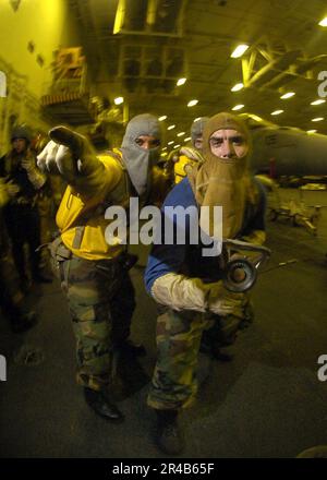 US Navy  An on-scene leader provides direction to a hose team member during a simulated fire in the hangar bay aboard the conventionally-powered aircraft carrier USS Kitty Hawk (CV 63). Stock Photo