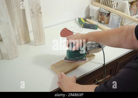 Woman's hands sanding a wooden board with an electric sander in her workshop at home Stock Photo