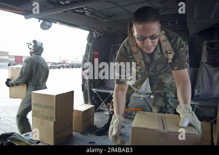 US Navy  U.S. Navy personnel and U.S. Air Force reservists work together to unload cases of water from a Navy SH-60 Seahawk helicopter at an airfield near Biloxi, Miss. Stock Photo