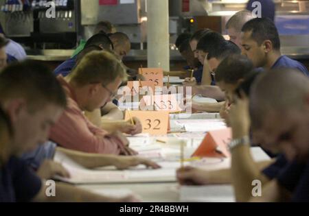 US Navy  Crew members take the E-5 Second Class Petty Officer advancement examination on the aft mess decks aboard the nuclear-powered aircraft carrier USS Nimitz (CVN 68). Stock Photo