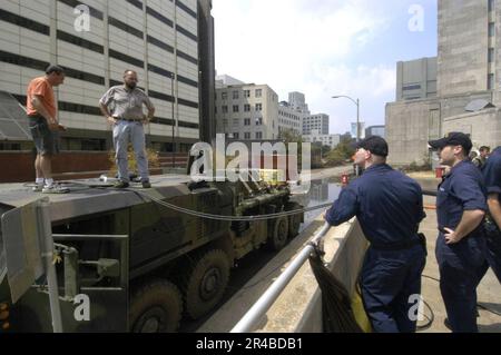 US Navy  Hull Technician 2nd Class and Electrician Mate 3rd Class make final preparations to energize electrical submersible pump powered by a hybrid electric truck. Stock Photo