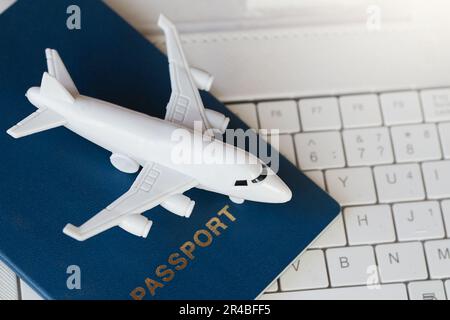 Model white airplane, white laptop and passport . Buying online ticket booking for travel concept Stock Photo