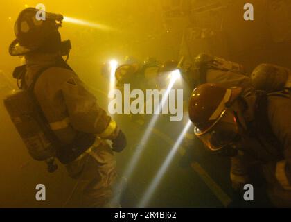 US Navy  Repair Locker One Alpha On-Scene Leader, Disbursing Clerk 3rd Class orders his hose team to lay down the fire hose at the conclusion of a ship-wide general quarters drill. Stock Photo