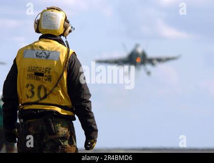 US Navy  An Aviation Boatswain's Mate watches as an F-A-18C Hornet as it prepares to land. Stock Photo