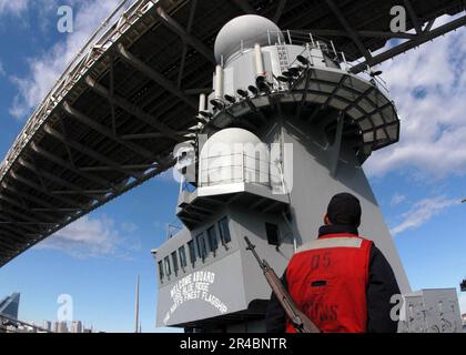 US Navy  Gunner's Mate Seaman watches as amphibious command ship USS Blue Ridge (LCC 19) narrowly passes under Tokyo's Rainbow Bridge. Stock Photo