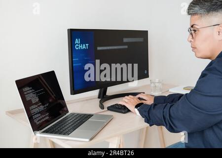 AI chatbot: Programmer using artificial intelligence for software development inside office - Virtual chat Bot technology trend - Focus on hands Stock Photo