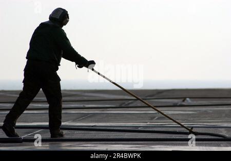 US Navy  An arresting gear crew member guides an arresting wire back into position as it is retracted on the flight deck aboard the Nimitz-class aircraft carrier USS Theodore Roosevelt (CVN 71). Stock Photo