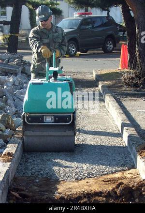 US Navy  Construction Electrician 2nd Class assigned to Naval Mobile Construction Battalion Four (NMCB-4), Det Atsugi, compacts the soil. Stock Photo