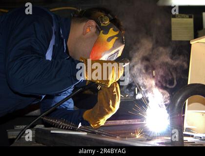 US Navy  Hull Technician 2nd Class welds a bracket together to hold oxygen tanks aboard the multi-purpose amphibious assault ship USS Bataan (LHD 5). Stock Photo