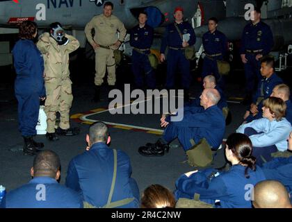 US Navy  Hull Technician 2nd Class left, explains how to don an Advanced Chemical Protective Garment (ACPG) as Personnel Specialist 3rd Class Shantrail Robinson demonstrates for a group of Sail. Stock Photo