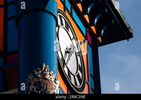 An upright blue post with an orange clock face mounted on its side Stock Photo