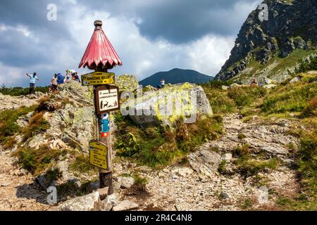 A signpost with a group of hikers resting on a rocky slope. Slovakian mountains. Stock Photo