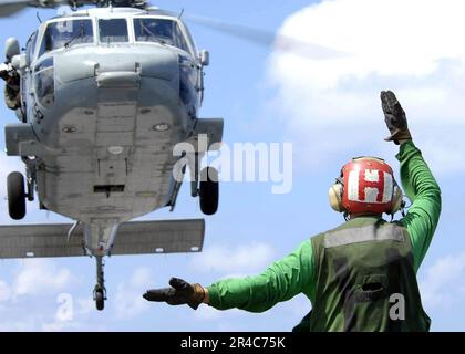 US Navy  An aircraft director guides an MH-60S Seahawk helicopter assigned to the. Stock Photo