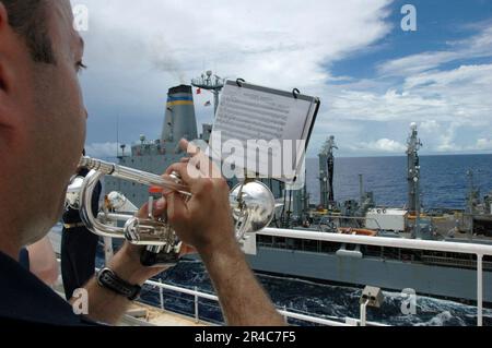 US Navy Musician 1st Class plays Anchors Away during an underway replenishment between the USNS Pecos and USNS Mercy Stock Photo