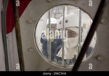 US Navy Damage control investigators, Republic of Singapore Navy (RSN) 2nd Sgt. and Damage Controlman Fireman approach a watertight door as they search for damage Stock Photo