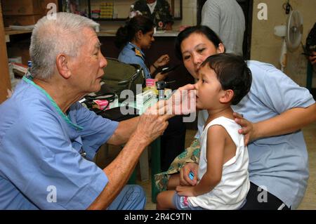 US Navy  a doctor with Aloha Medical Mission, examines a boy at Camp Batista during a Medical and Dental Civil Action Project hosted by the U.S. Military Sealift Command (MSC) Hospital ship USNS. Stock Photo