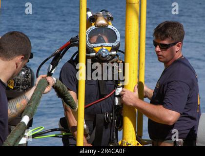 US Navy Chief Navy Diver and Navy Diver 1st Class stage handle Master Sgt. from the Republic of Singapore Navy (RSN) prior to conducting a dive Stock Photo