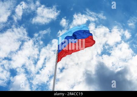 Flag of the self-proclaimed Lugansk People's Republic (LPR or LNR) is waving in front of blue sky and clouds Stock Photo