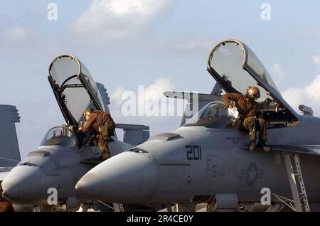 US Navy  Air wing Sailors embarked aboard the conventionally-powered aircraft carrier USS Kitty Hawk (CV 63) clean the canopy and cockpit of F-A-18 Super Hornets. Stock Photo