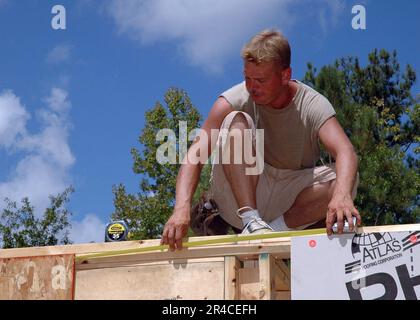 US Navy Utilitiesman 1st Class site manager for the Habitat For Humanity project, measures the space where the final wall panel will be placed before roof panels are installed Stock Photo