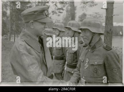 SS Photographer Ahrens captures the intensity and brutality of the Kavallerie operations in Russia during  May and June 1943, providing a haunting glimpse into the grim realities of war through his lens. Senior officers in dress uniforms with awards, wounded soldiers in war hospital; soldiers with Russian civilians; awards ceremonies, landscapes, saw mill, terrain table exercise, fighting positions, soldiers relaxing and swimming, infantry squad field training, propaganda material being handed out to Russian civilians, burning village, assault gun unit, field barracks scenes. Images depicting Stock Photo