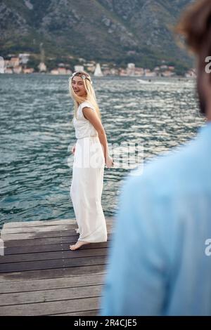 Happy newlywed couple on wooden jetty by sea. Beautiful bride feeling joyful. Newlywed coupe on honeymoon. Wedding, honeymoon, love concept Stock Photo