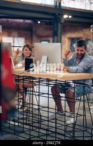 Creative young man and woman workers in modern office space coming up with great ideas for their project, feeling joyful. Business concept. Stock Photo