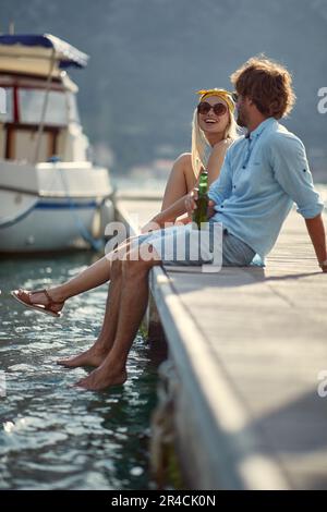 young couple sitting on the dock and enjoys by the lake Stock Photo