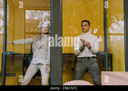 Two business colleagues goofing off in the phone booths at the office Stock Photo