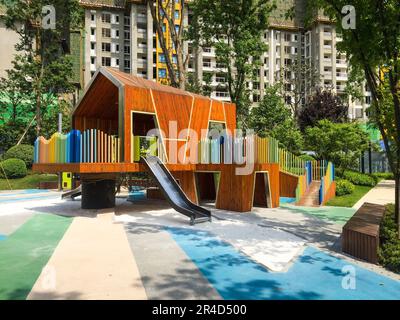 This image captures an outdoor playground with a large overhead swing structure and multicolored slides Stock Photo