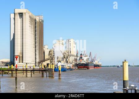 Bulk carrier ships moored to a commercial dock on a river harbour on a clear summer day Stock Photo