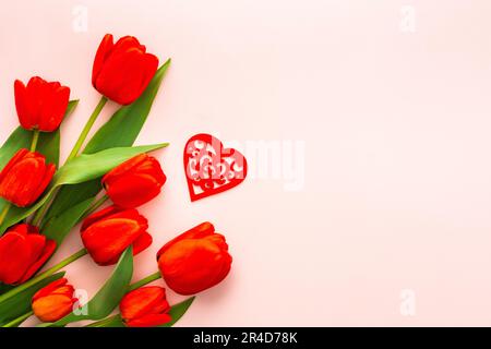 Fresh red tulips and hearts on pink background, concept of spring and holidays or Valentine's Day, top view, copy space Stock Photo