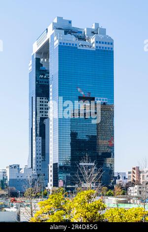 The landmark Umeda Sky Building on a sunny day in the spring with clear blue sky behind. Another office blocks with cranes on reflected in the facade. Stock Photo