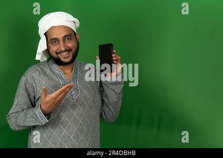 Young Indian Farmer Showing His Mobile on Left Hand In Green Screen, Copy Space Stock Photo