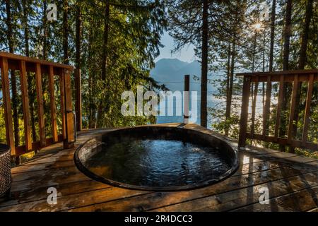 Wooden hot tub overlooking lake in morning. Stock Photo