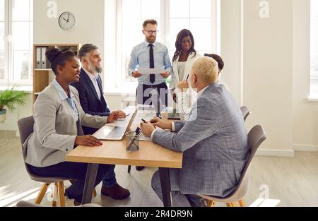 Diverse business people talking on a meeting sitting at the working place in office. Stock Photo