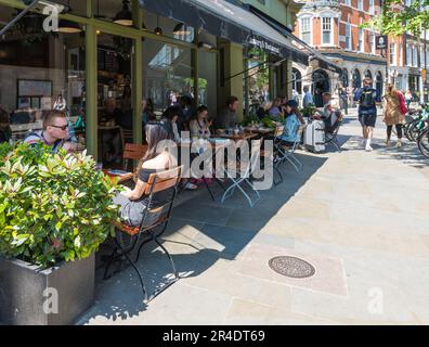 People enjoying food and drink seated at pavement tables outside Le Pain Quotidien restaurant on Marylebone High Street, London, England, UK Stock Photo