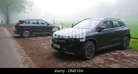 Uelsen, Germany - May 15 2023 Two similar cars parked beside each other on a foggy day. Both are black all electric Mercedes Benz EQA 250 Stock Photo