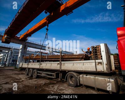 Podolsk, Moscow province - August 02, 2021: Pipes warehouse. Worker load tubes on truck with overhead crane. Stock Photo