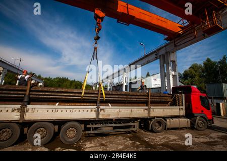 Podolsk, Moscow province - August 02, 2021: Pipes warehouse. Workers loads pipes on truck with overhead crane Stock Photo